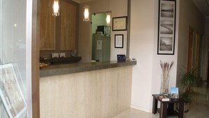 A reception area with a counter, framed certificates, and a small table with a plant. - Hostal Albero by eme hoteles (Sanlucar la Mayor)