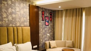 Una camera d'albergo con un letto grande, un divano, un tavolino rotondo e una ventola a soffitto.