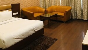 Una camera d'albergo con un letto, due poltrone, un tavolino e una ventola a soffitto.