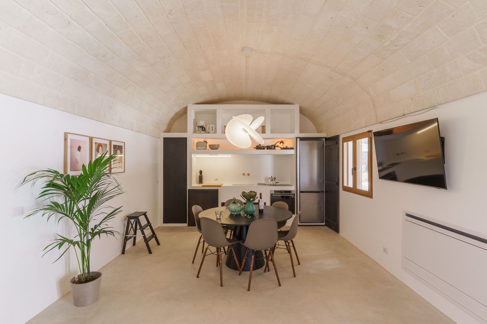 Una cocina moderna con una isla central, electrodomésticos integrados y una zona de comedor con una mesa redonda y sillas.