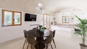 A modern dining area with a round table, chairs, and a TV mounted on the wall.
