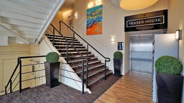A staircase with a handrail, a painting on the wall, and a sign that reads "FRASER HOUSE". - Stunning 1 bedroom short term let in Aberdeen city center close to all amenities (Aberdeen)