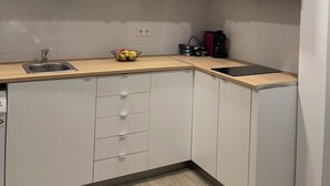Una cocina moderna con armarios de madera clara, un lavamanos de acero inoxidable y encimera negra.