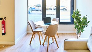 Una habitación moderna con una mesa de comedor y sillas, un sofá, una planta en maceta y un extintor en la pared.
