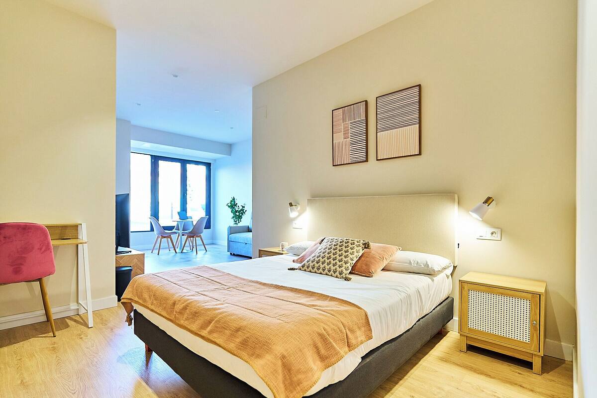 Un dormitorio moderno con una cama grande, lámparas de noche y vistas a un comedor.