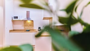 Una cocina moderna con armarios blancos, microondas, hervidor y cafetera.