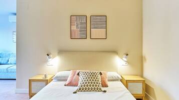 A neatly made bed with a patterned pillow, two bedside tables with lamps, and two wall-mounted artworks.