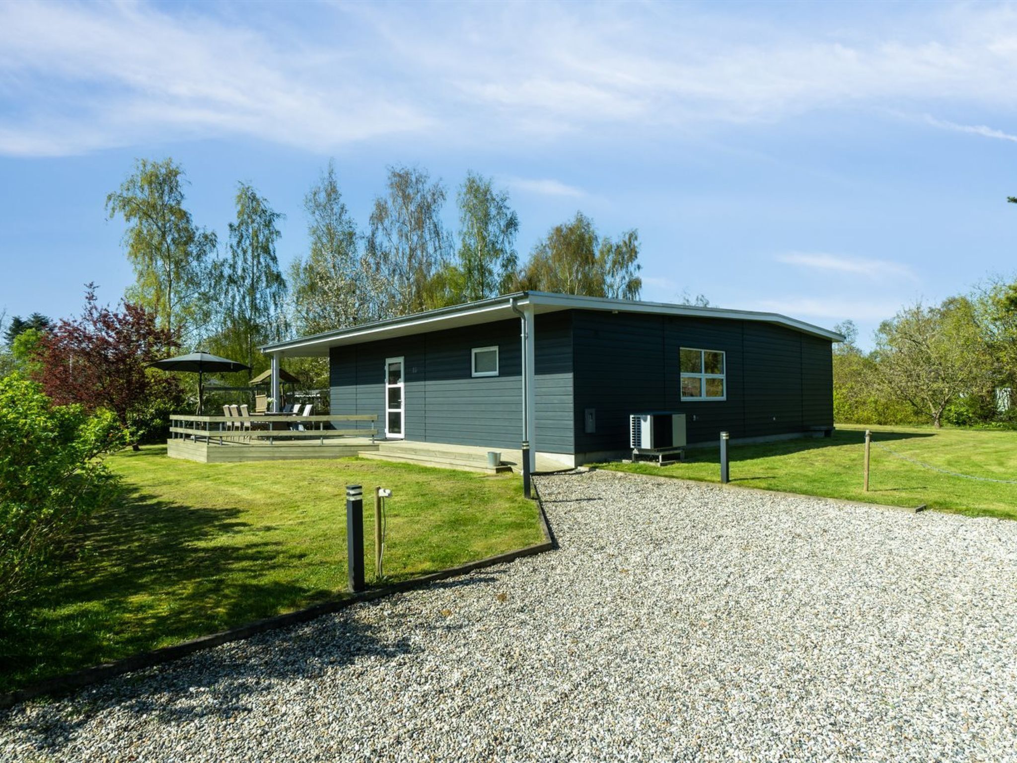 A modern, single-story building with a gravel driveway and a covered outdoor seating area.