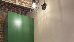 Um banheiro com armário verde, pia branca, torneira de latão, frasco de sabonete líquido e torradeira branca.