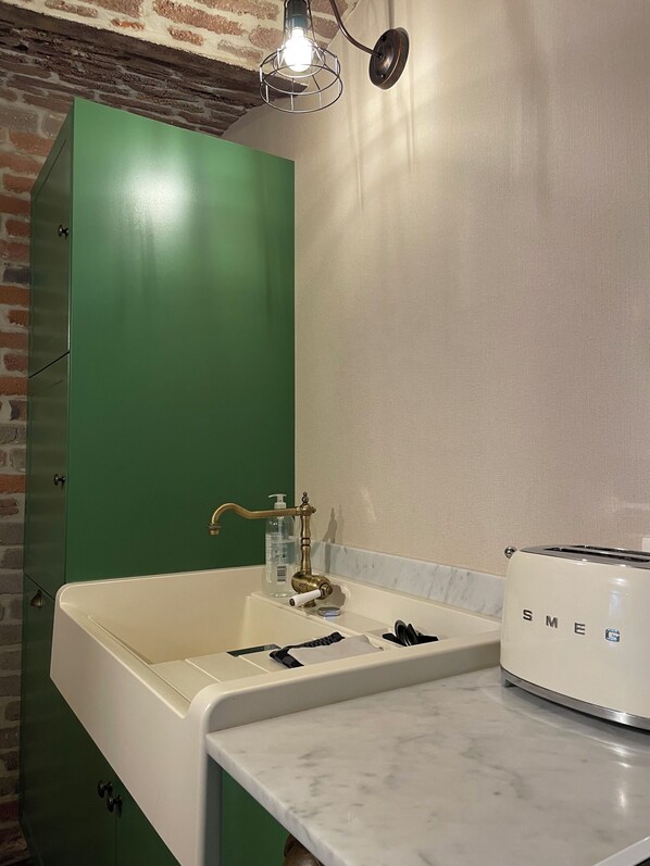 A bathroom with a green cabinet, a white sink, a brass faucet, a bottle of hand soap, and a white toaster. - Le petit Second, a charming vacation home for 2 people in the center of Spa (Spa)