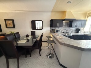 Una cocina moderna con una isla central, armarios oscuros y salpicadero de azulejos.