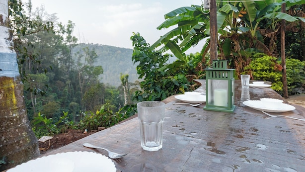 A table set outdoors with a glass, plates, and a lantern. - Last Villa (Madikeri)