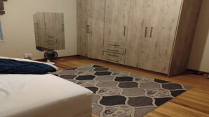 Un dormitorio con cama, armario, ventilador y alfombra estampada.