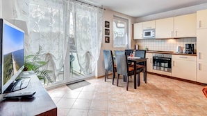 A modern kitchen with a microwave, oven, and dining area. - Cozy vacation apartment with balcony near the beach and center (Ückeritz)