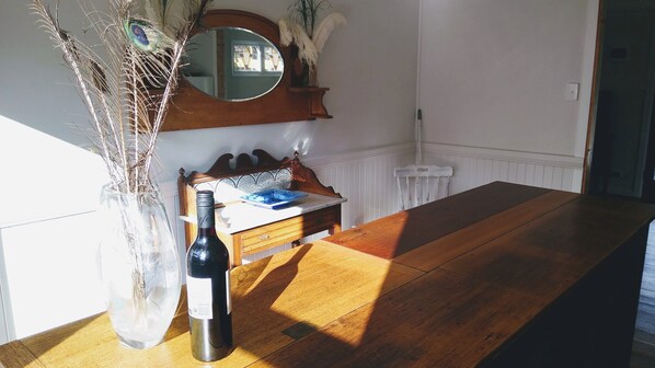 Un tavolo da pranzo in legno con una bottiglia di vino e un vaso con piante essiccate.