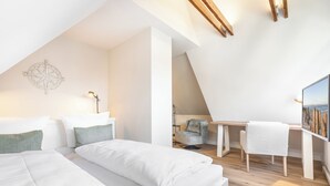 Un dormitorio moderno y bien iluminado con una cama grande, un escritorio y una silla.