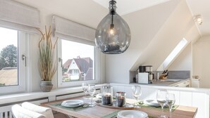 Una cocina moderna con comedor, ventanas amplias y vistas a casas.