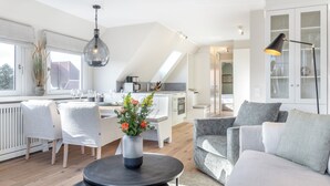Una sala de estar moderna con comedor, cocina y vistas al exterior.