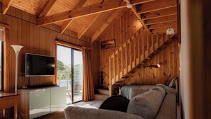 A cozy cabin interior with a sofa, a TV, and a desk. - Geoff's ~ beach, bush and bliss (Break O'Day)