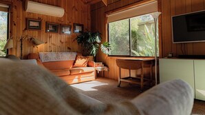 A cozy room with wooden walls, a sofa, a desk, a plant, and a TV. - Geoff's ~ beach, bush and bliss (Break O'Day)