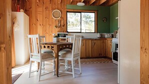 A wooden interior with a dining table and chairs, a kitchen with wooden cabinets, a refrigerator, and a window. - Geoff's ~ beach, bush and bliss (Break O'Day)