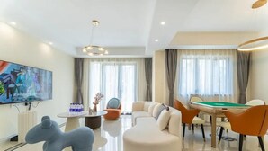 Een moderne hotelkamer met een biljarttafel, comfortabele zitplaatsen, een grote televisie en een eethoek.