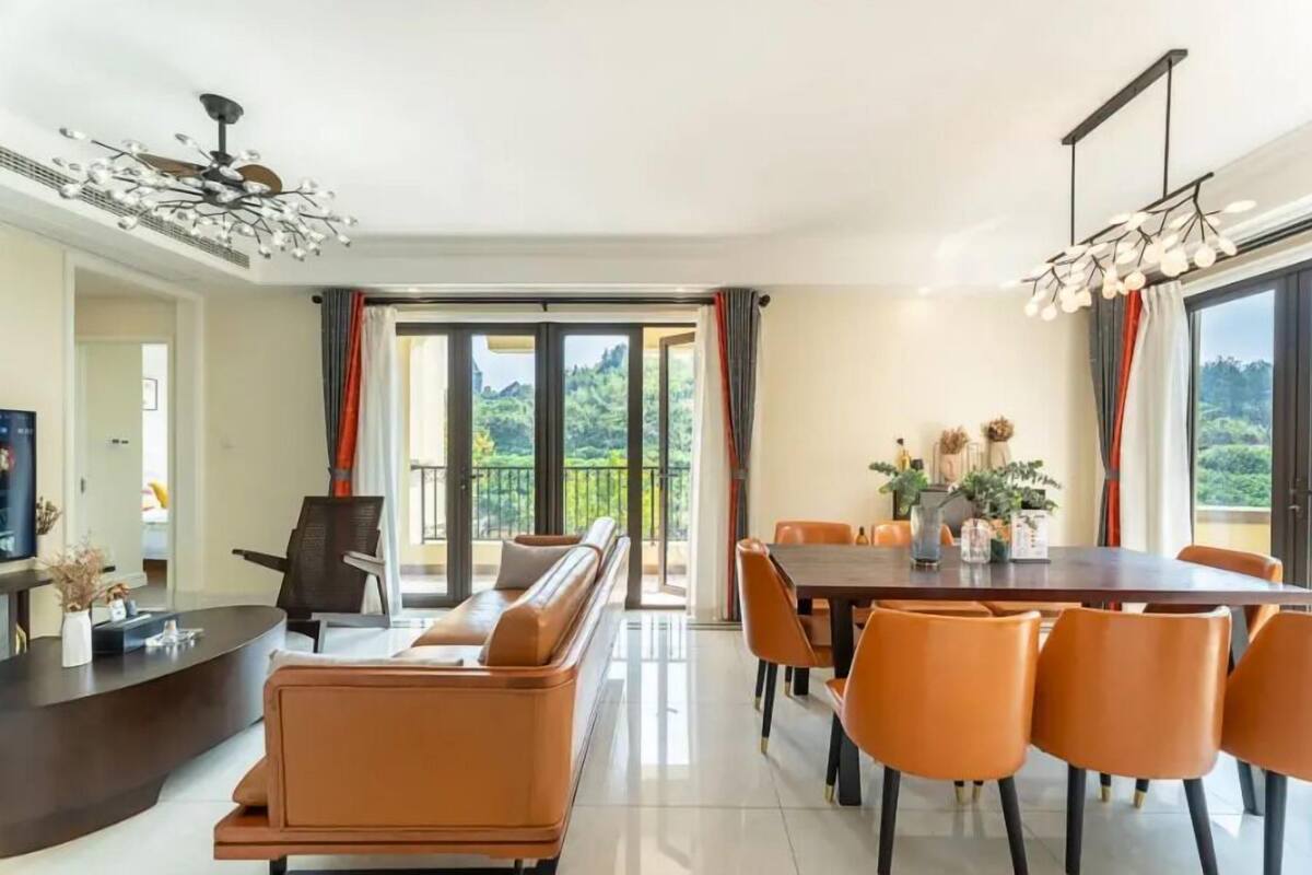 Un salon moderne avec un canapé, une table à manger et des chaises. On y trouve également un téléviseur et une plante posée sur la table.