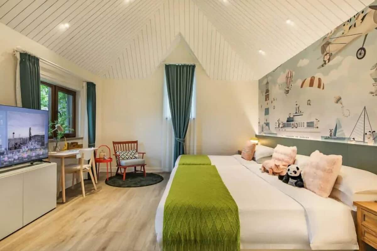 Une chambre d’hôtel moderne dotée d’un grand lit, d’une télévision, d’un bureau et d’une fresque murale.