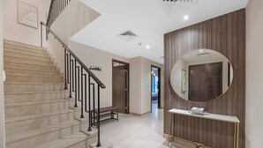 A modern interior with a marble staircase, a console table, and a round mirror. - Durrani Homes - The Luxe Retreat 4BR Podium villa with private Jacuzzi and Burj Khalifa View (Dubai)