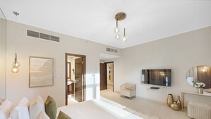 A modern bedroom with a large bed, a TV, and a minimalist decor. - Durrani Homes - The Luxe Retreat 4BR Podium villa with private Jacuzzi and Burj Khalifa View (Dubai)
