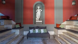 A modern interior with a central seating area, a statue, and a staircase. - CORTE SATRIANO RESIDENCE (Naples)
