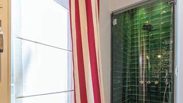 A shower with green tiles and a red and white striped curtain.