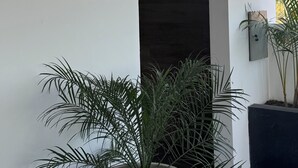 A modern building entrance with a sign indicating a bathroom and sauna. There are potted plants near the entrance. - Serene studio with Pool and Wifi in charming Tarija (Tarija)