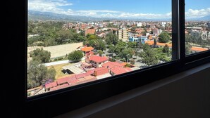 A view from a window overlooking a cityscape with buildings and greenery. - Serene studio with Pool and Wifi in charming Tarija (Tarija)