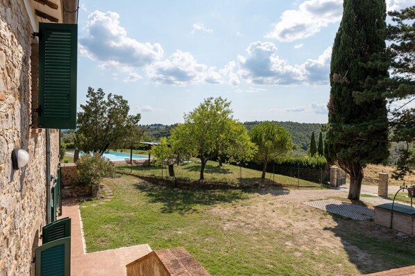 A stone building with a pool, trees, and a view of the countryside.