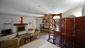 A spacious living room with a fireplace, wicker furniture, and a wooden spiral staircase. - Lovely house with AC in Matera - Perfect for a getaway (Matera)