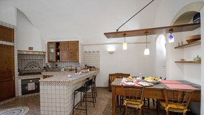 A kitchen with a central island, wooden cabinets, and a dining area with a table and chairs. - Lovely house with AC in Matera - Perfect for a getaway (Matera)