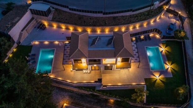A modern resort with a pool area, outdoor seating, and a well-lit entrance. - VILLA PENELOPE
 (Katouna)