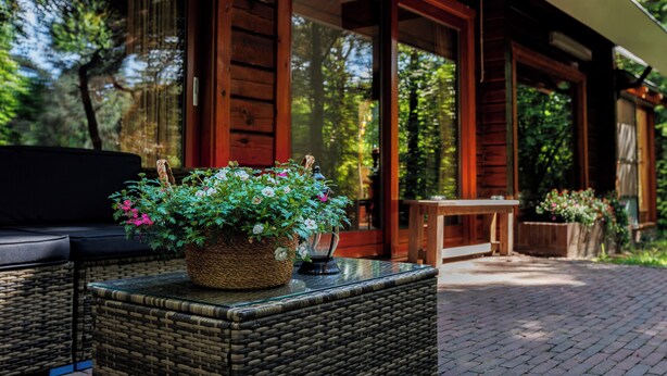 A wicker table with a potted plant and a lantern on a veranda. - Spectacular Dune Villa with a private sauna and breathtaking views of the dunes (Soest)