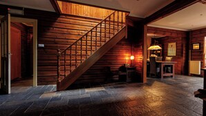 A wooden interior with a staircase, stone flooring, and a table with a lamp. - Spectacular Dune Villa with a private sauna and breathtaking views of the dunes (Soest)