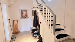 A staircase with a handrail and a metal rack holding a broom and a vacuum cleaner. - Fully equipped vacation apartment with plenty of space, barbecue and garden, centrally located (Waltershausen)