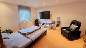 A bedroom with a bed, a chair, a TV, a mirror, and a small table with items on it. - Fully equipped vacation apartment with plenty of space, barbecue and garden, centrally located (Waltershausen)