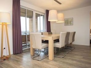 Ein moderner Essbereich mit einem Holztisch, sechs Stühlen und Pendelleuchten.