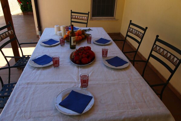 Una mesa para cuatro personas, con platos, servilletas y un frutero.