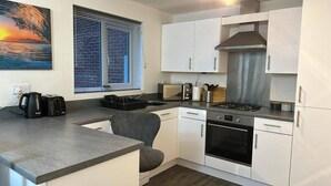 Una kitchenette compacta con microondas, tostadora, hervidor y estufa.