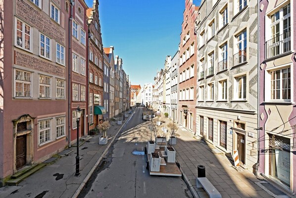 Une rue bordée de bâtiments historiques, avec un ciel dégagé et une route paisible, ombragée par des arbres.