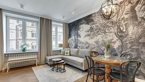 Een moderne woonkamer met een bank, een eettafel met stoelen, een lange bank en een groot raam met gordijnen.