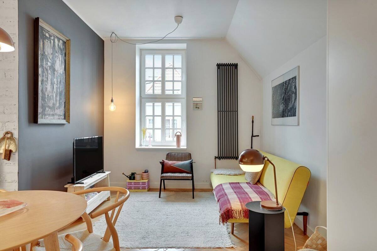A cozy living room with a television, a dining table, a sofa, and a window with a view of the outside.