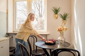 A person at a table with a plate of food, a vase with flowers, and two wall-mounted planters. - Old Town Ogarna Baltus by Downtown Apartments (Gdansk)
