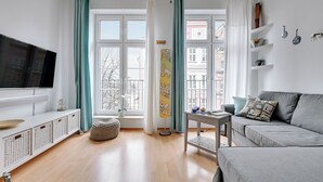Een moderne woonkamer met een grote flatscreen televisie, een grijze bank en een houten vloer.